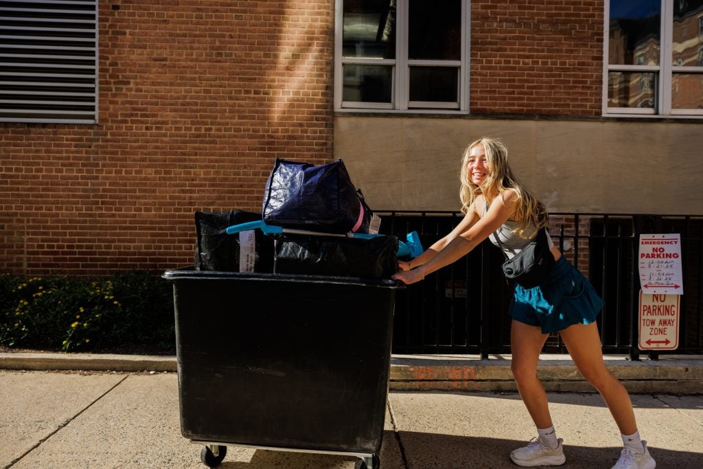 A student pushes a cart of luggage