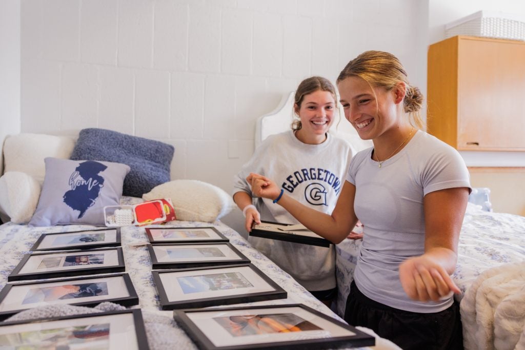 Two students look at two rows of frames laid on a bed
