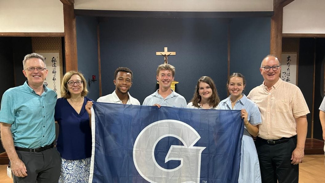 GU students hold a GU flag in a chapel