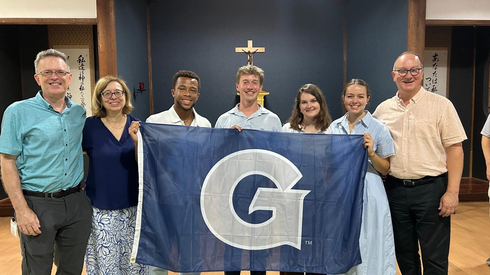 GU students hold a GU flag in a chapel