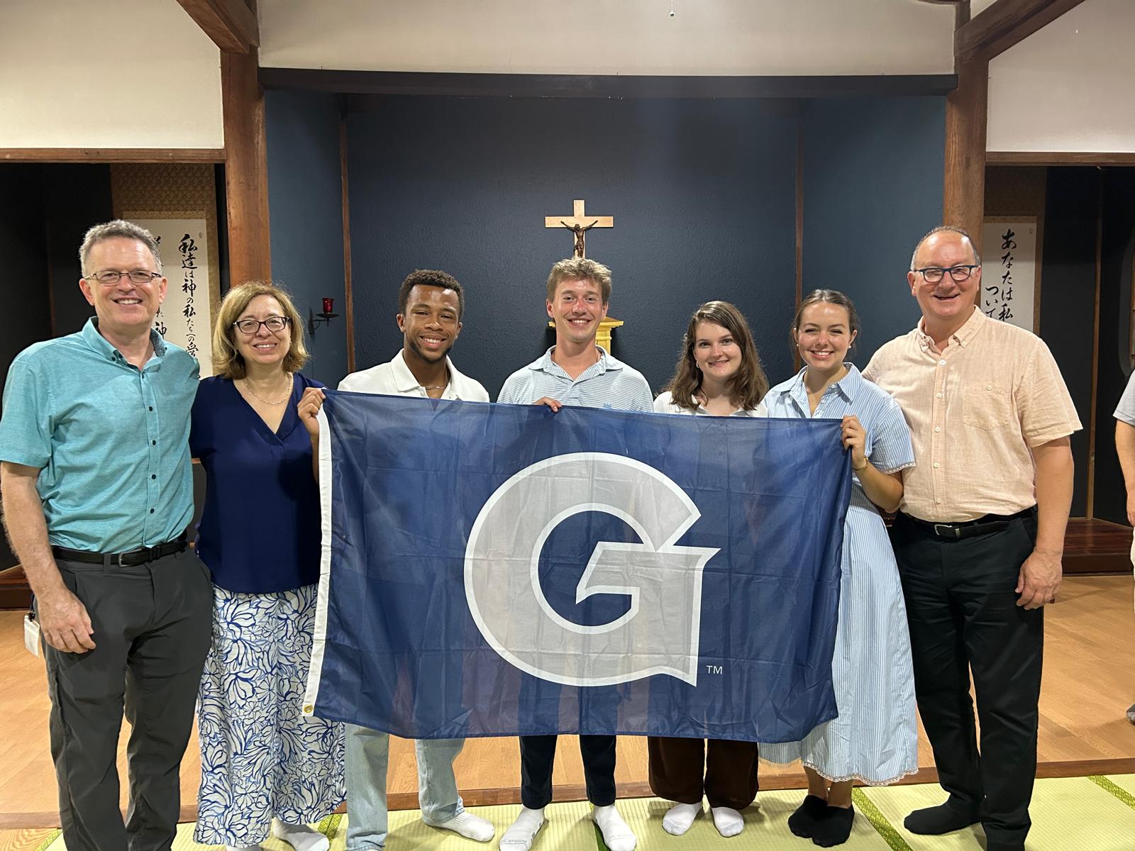 GU students hold a GU flag in a chapel