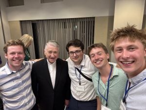 Luke with a few GU students and an older man wearing a suit