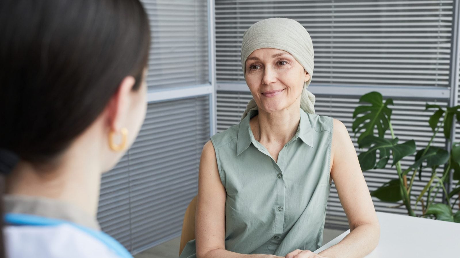 A woman wearing a scarf on her head smiles at a doctor&#039;s office.