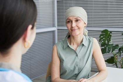 A woman wearing a scarf on her head smiles at a doctor&#039;s office.