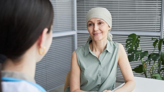 A woman wearing a scarf on her head smiles at a doctor&#039;s office.