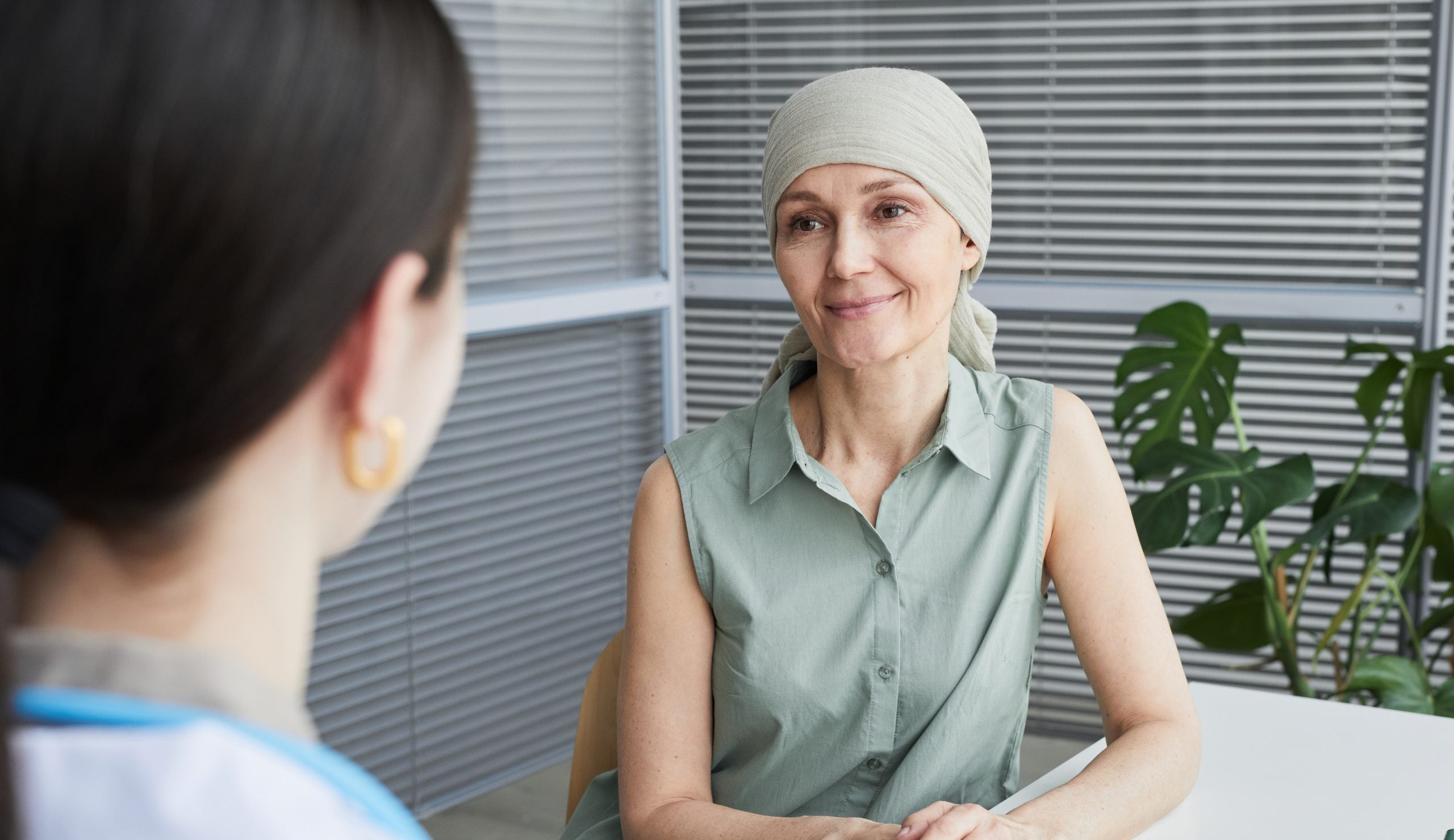 A woman wearing a scarf on her head smiles at a doctor's office.