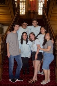 A group of students smile and pose together on a staircase