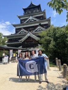 GU students holding a GU flag in front of a Japanese castle