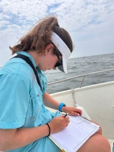 A female student takes notes on a boat