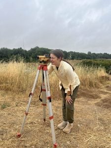 Caroline using a tool at an archaeological site