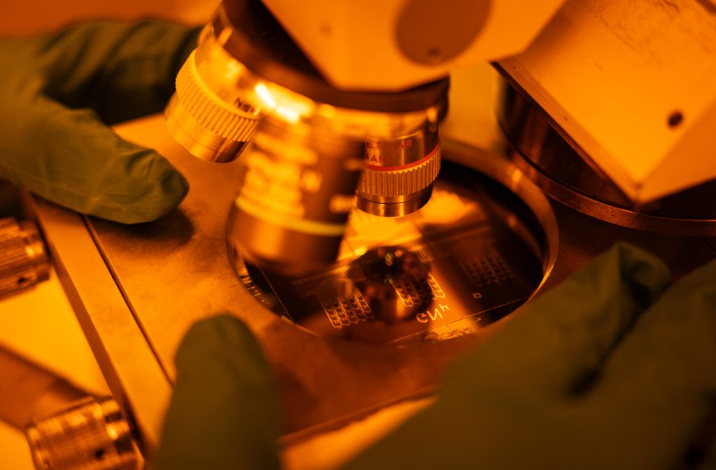 A microscope looking at a subject with gloved hand surrounding the device