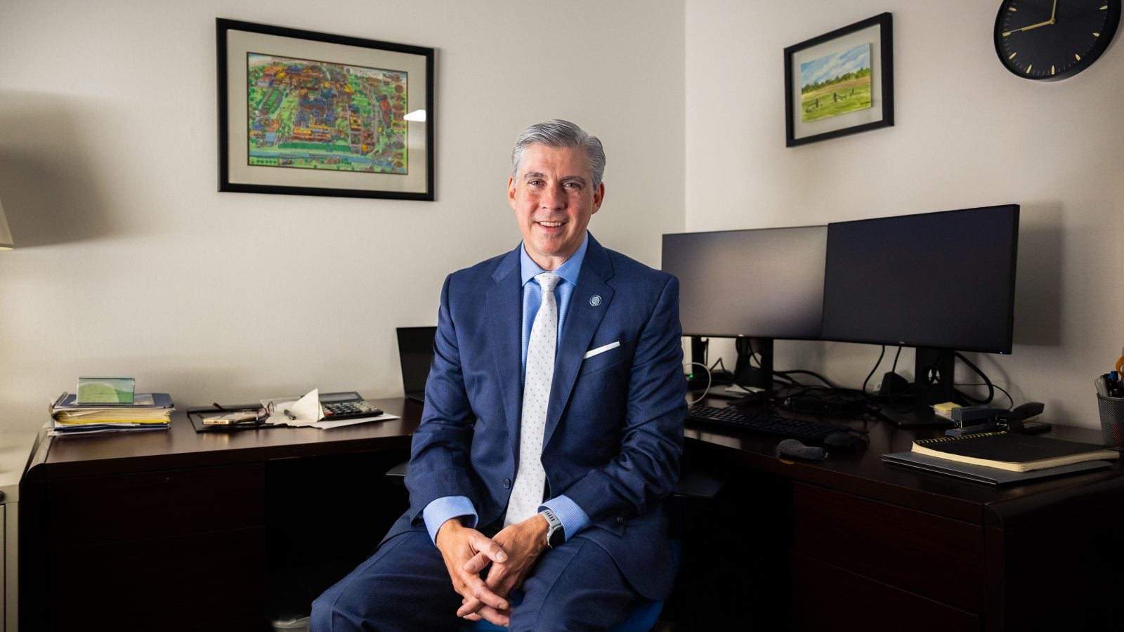 A man sits at his desk in a suit