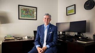 A man sits at his desk in a suit