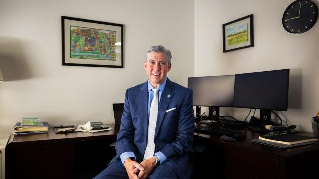 A man sits at his desk in a suit
