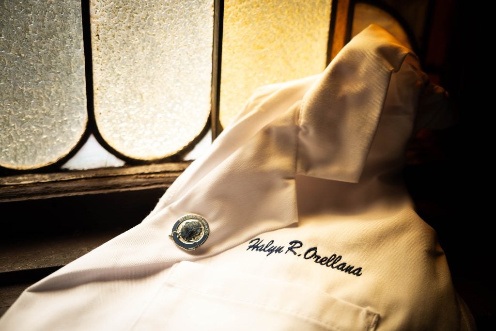 A close-up of a student's white coat by a stained glass window