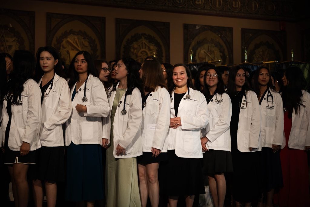 A group of students smile in medical white coats