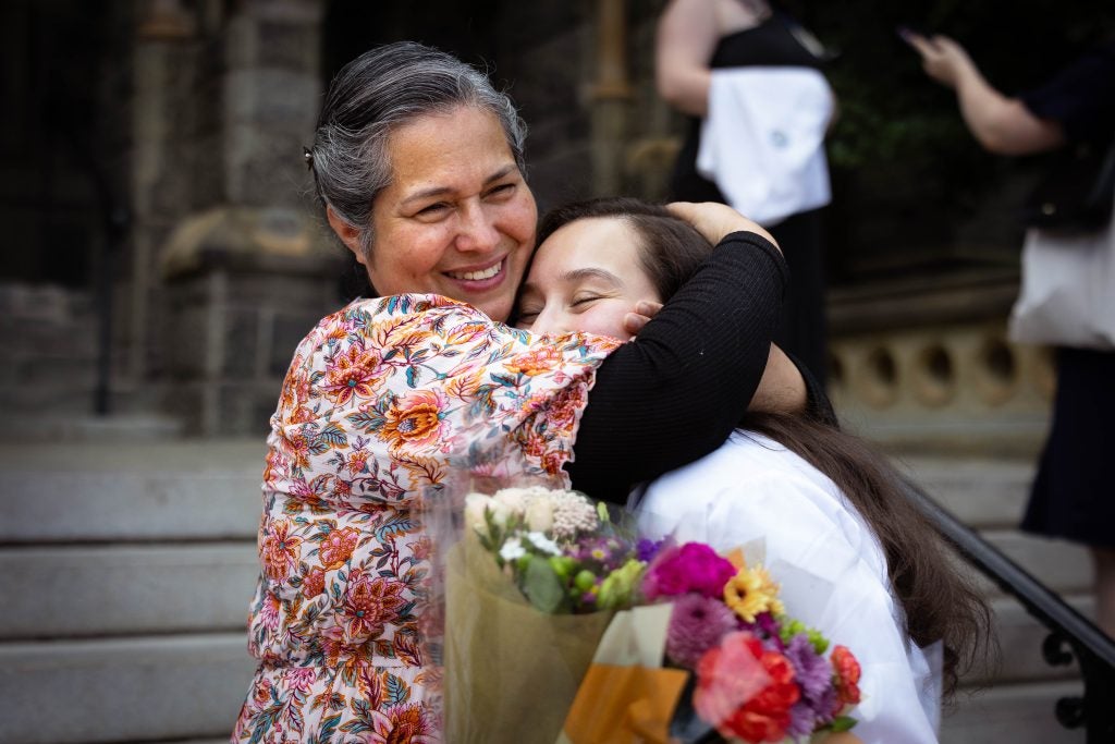 A mother and daughter hug each other and smile
