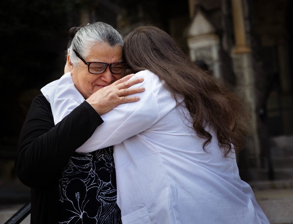 A grandmother and granddaughter hug each other as the grandmother cries