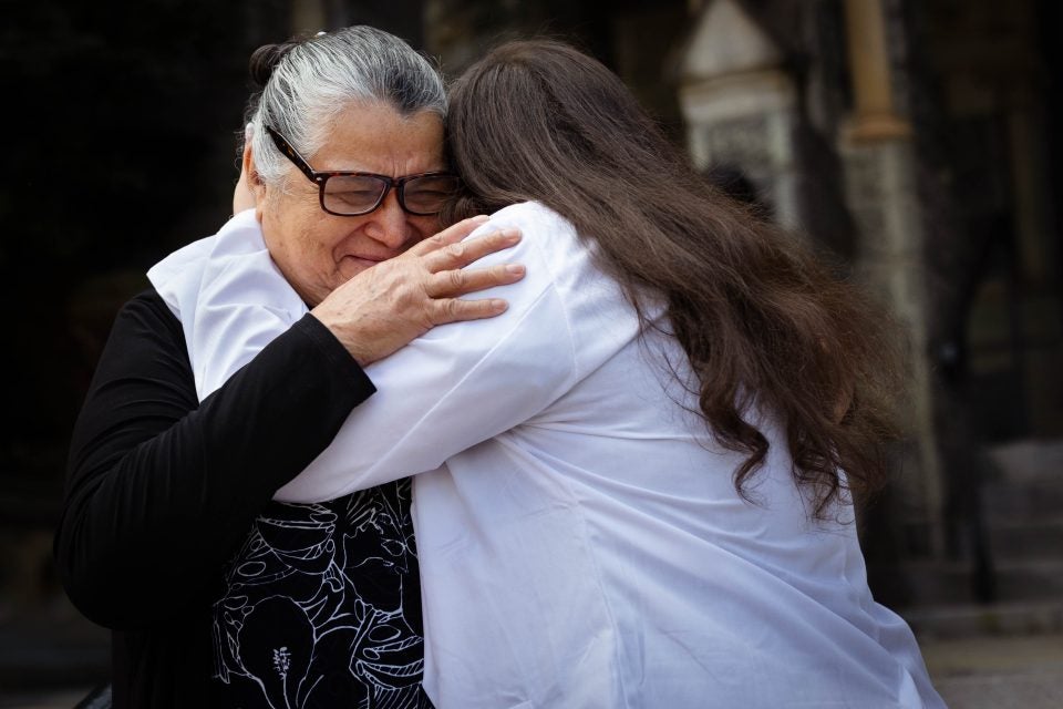 A grandmother cries while hugging her granddaughter