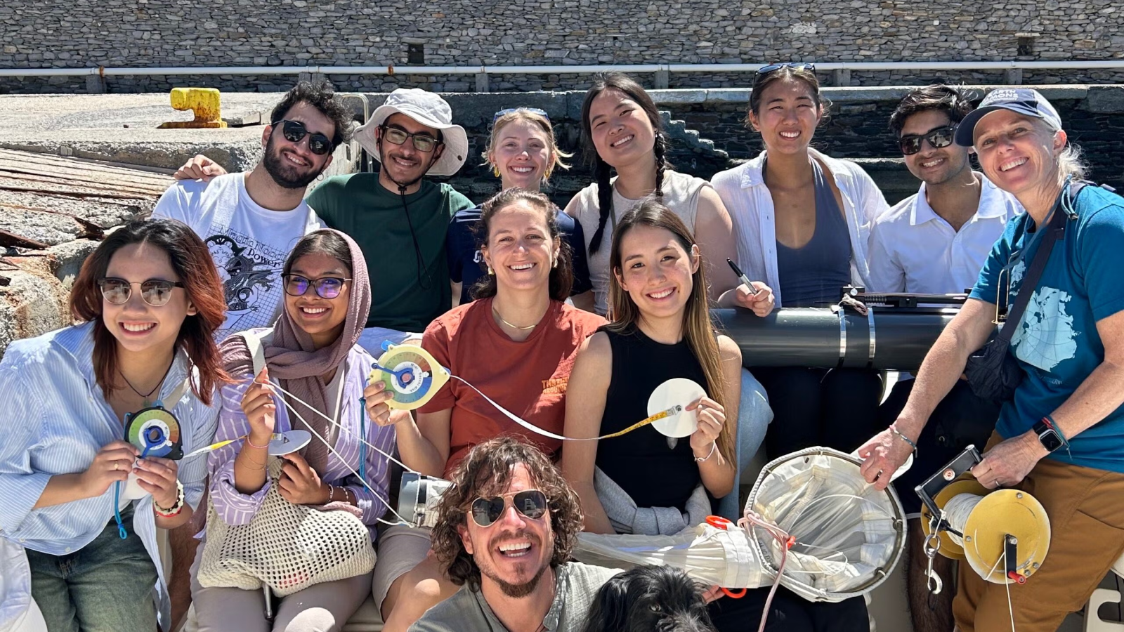 A group of students smile on a boat with a dog