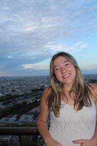 Ninabella in a white shirt overlooking a city during blue hour