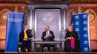 Three people sit on a stage at Georgetown