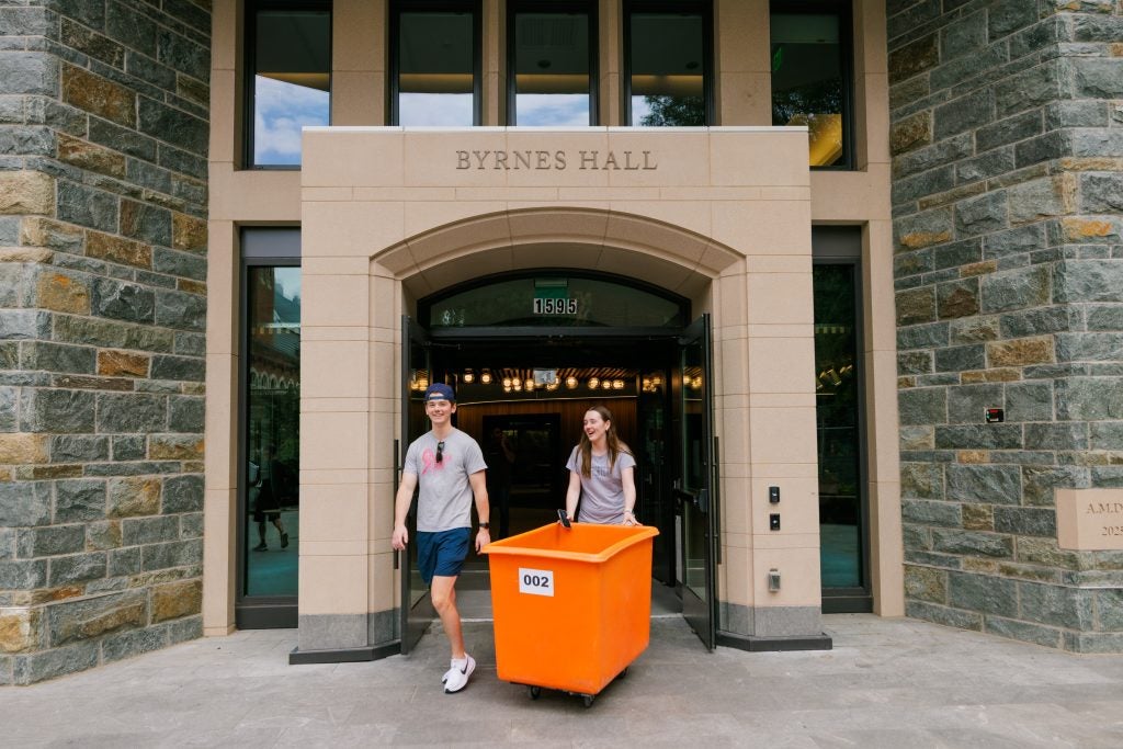 Students with a bin moving into dorm