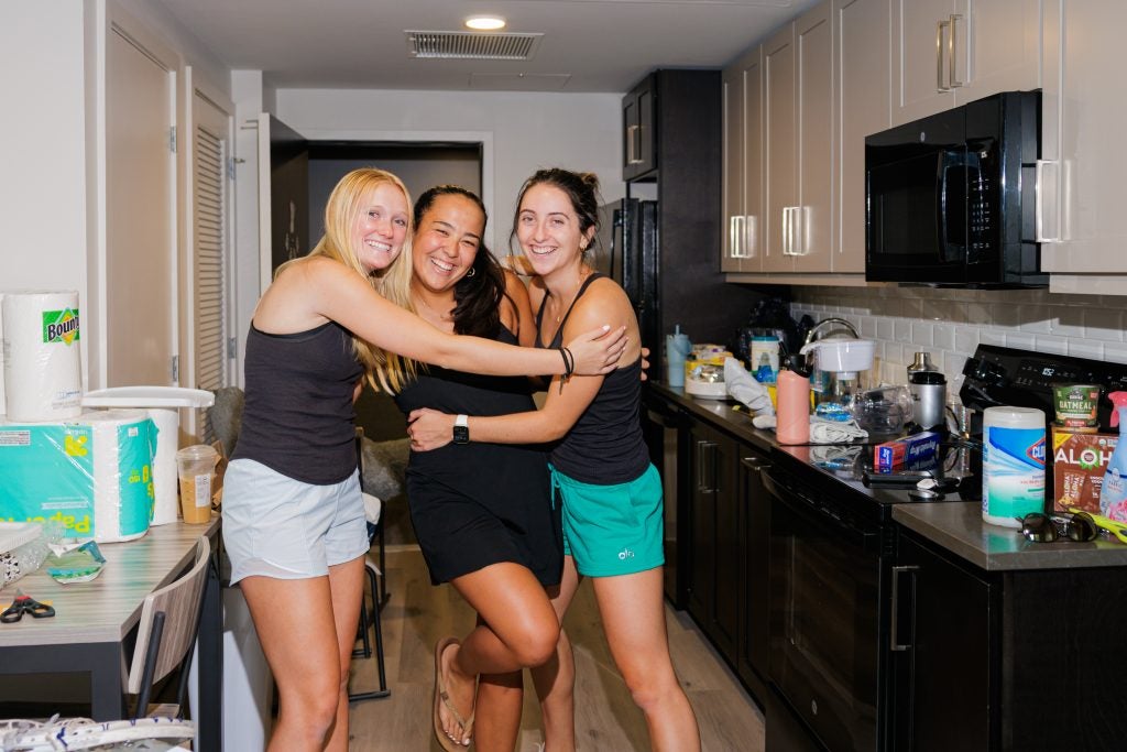three young women hug in an apartment