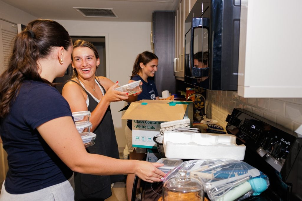 Two students unpack kitchen supplies in a dorm