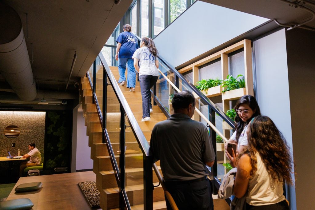Students and parents walk up a staircase in a modern building