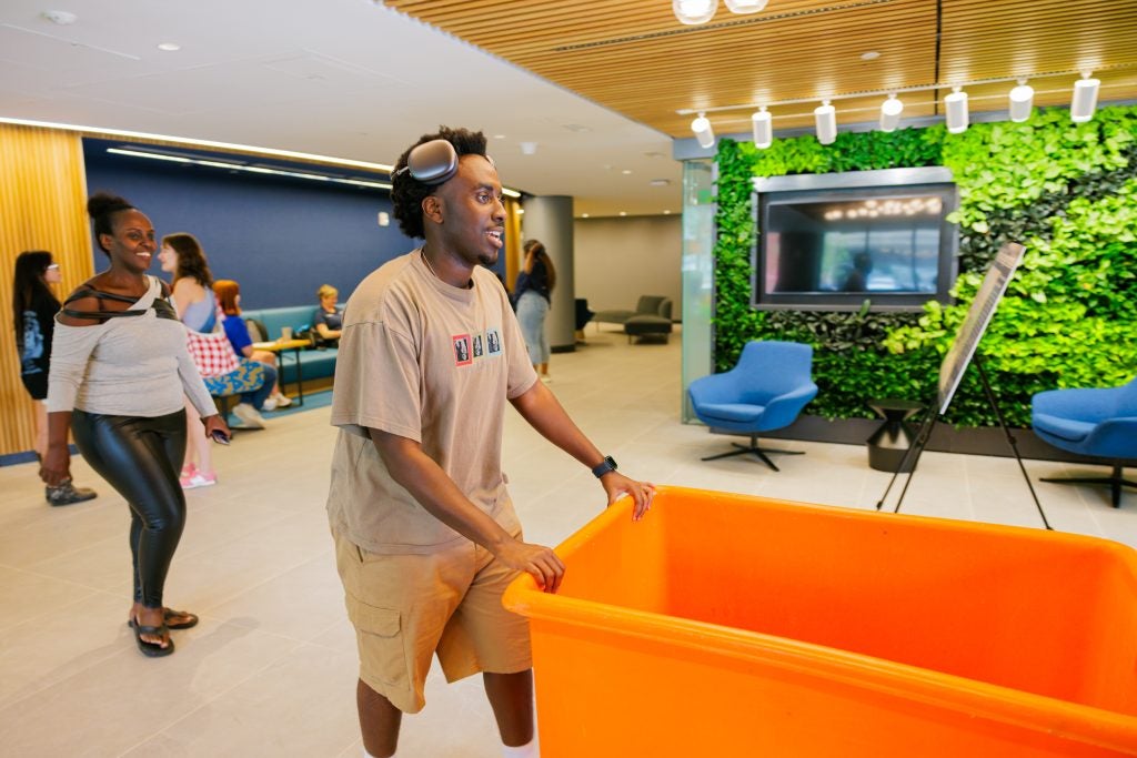 Student with orange moving bin in a dorm