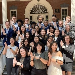 Students in business attire holding up a hand sign.