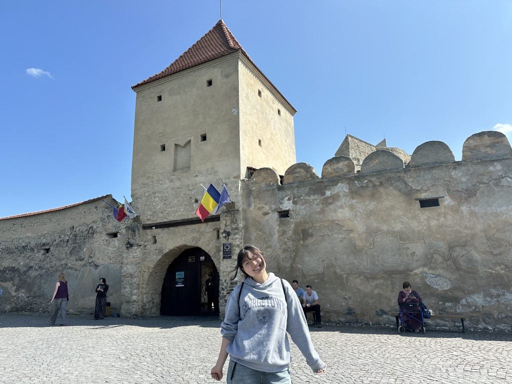 Young Asian woman in front of a medieval castle in Romania
