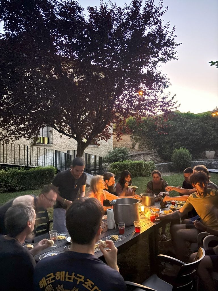Group of people gather around a table after sunset for a meal