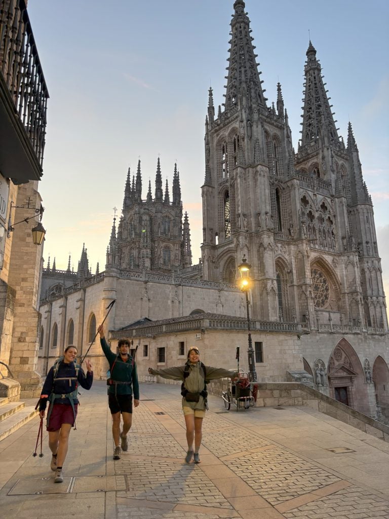 People walking past a large church in Spain after sunset