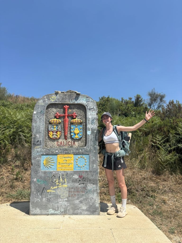 Young woman in athletic clothing next to a slab of stone with Spanish on it
