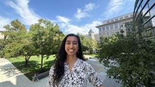 A female student smiles on a green campus