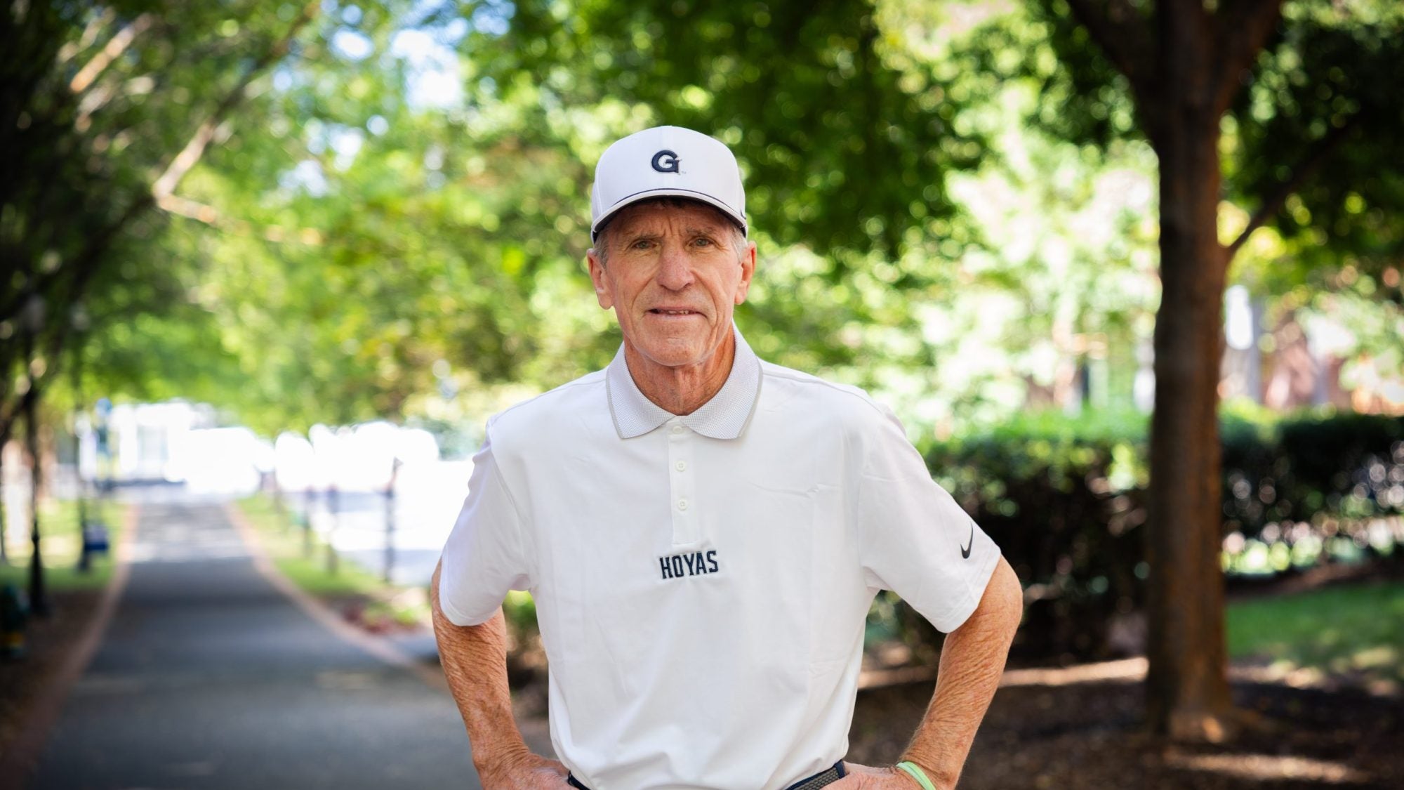 Older Caucasian man in a white hat and GU shirt with hands on hips
