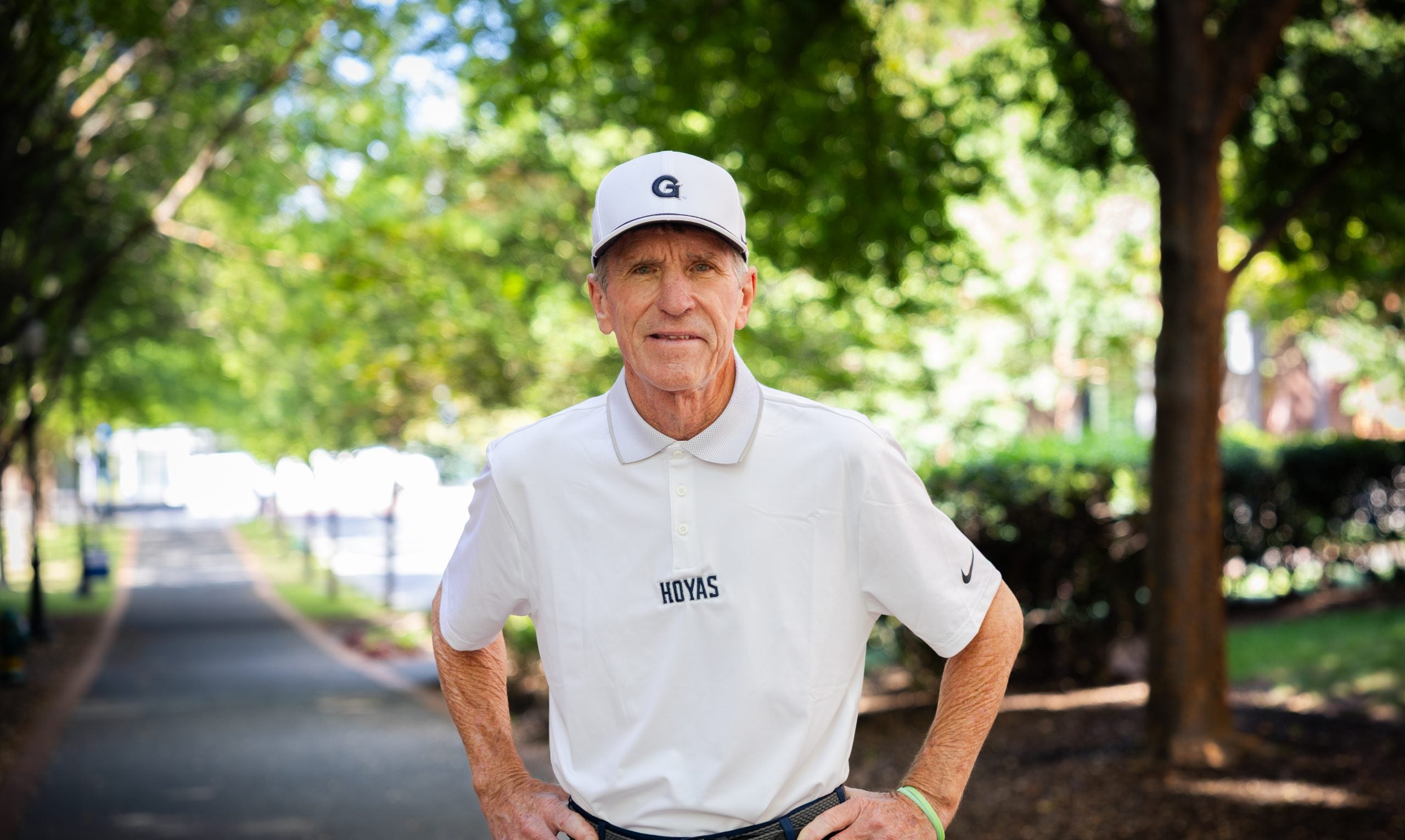 Older Caucasian man in a white hat and GU shirt with hands on hips