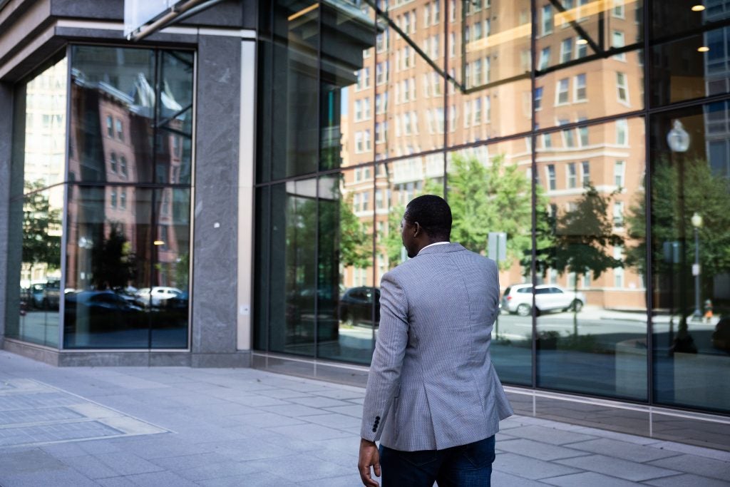 A man walks outside a window with glass windows.