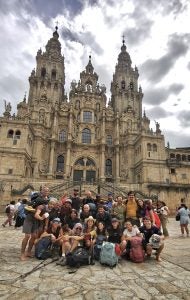 Group of people in hiking gear in front of a renaissance ere building in Spain