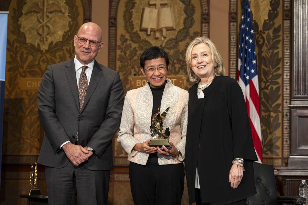 Maria Ressa with a trophy flanked by Joel Hellman and Hillary Clinton