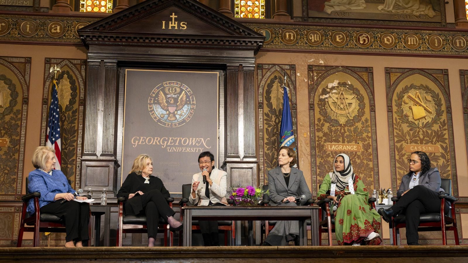 Panelists speak on stage in Gaston Hall
