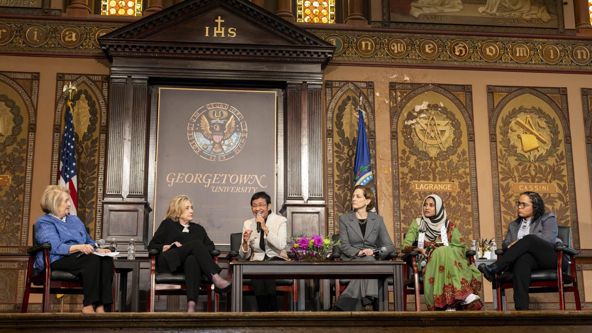 Panelists speak on stage in Gaston Hall