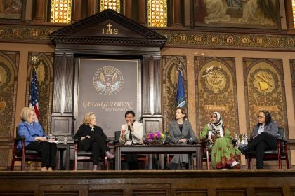 Panelists speak on stage in Gaston Hall