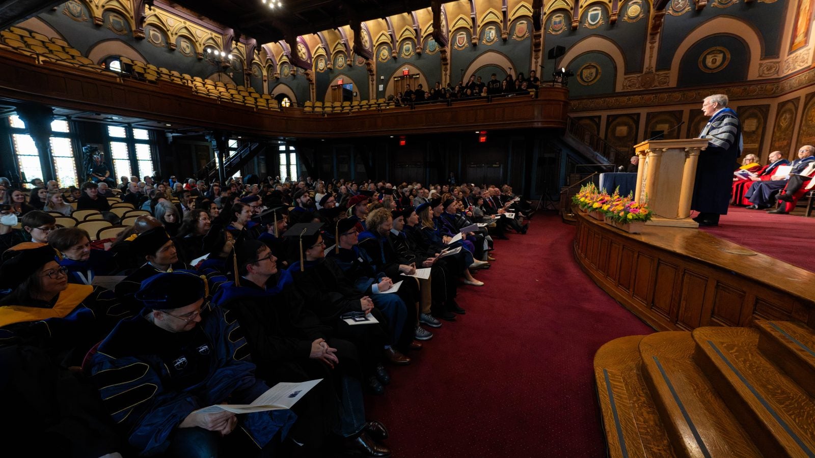 A view of an audience in a formal setting listening to a speaker