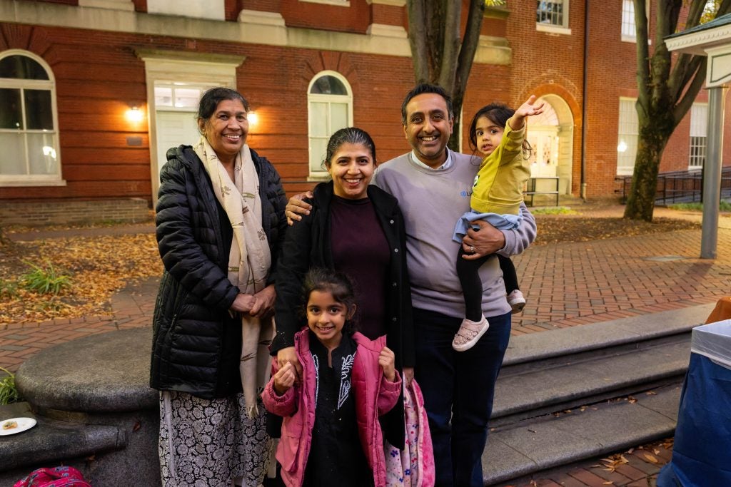 A family smiles outdoors in front of stone steps
