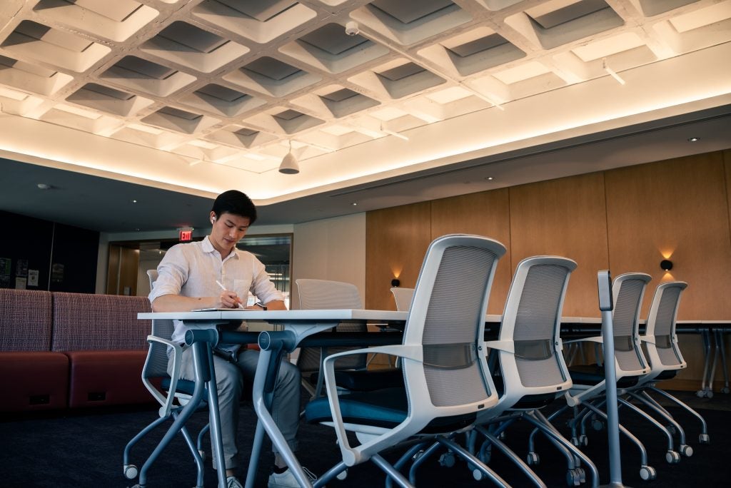 Young Asian man writing at a table