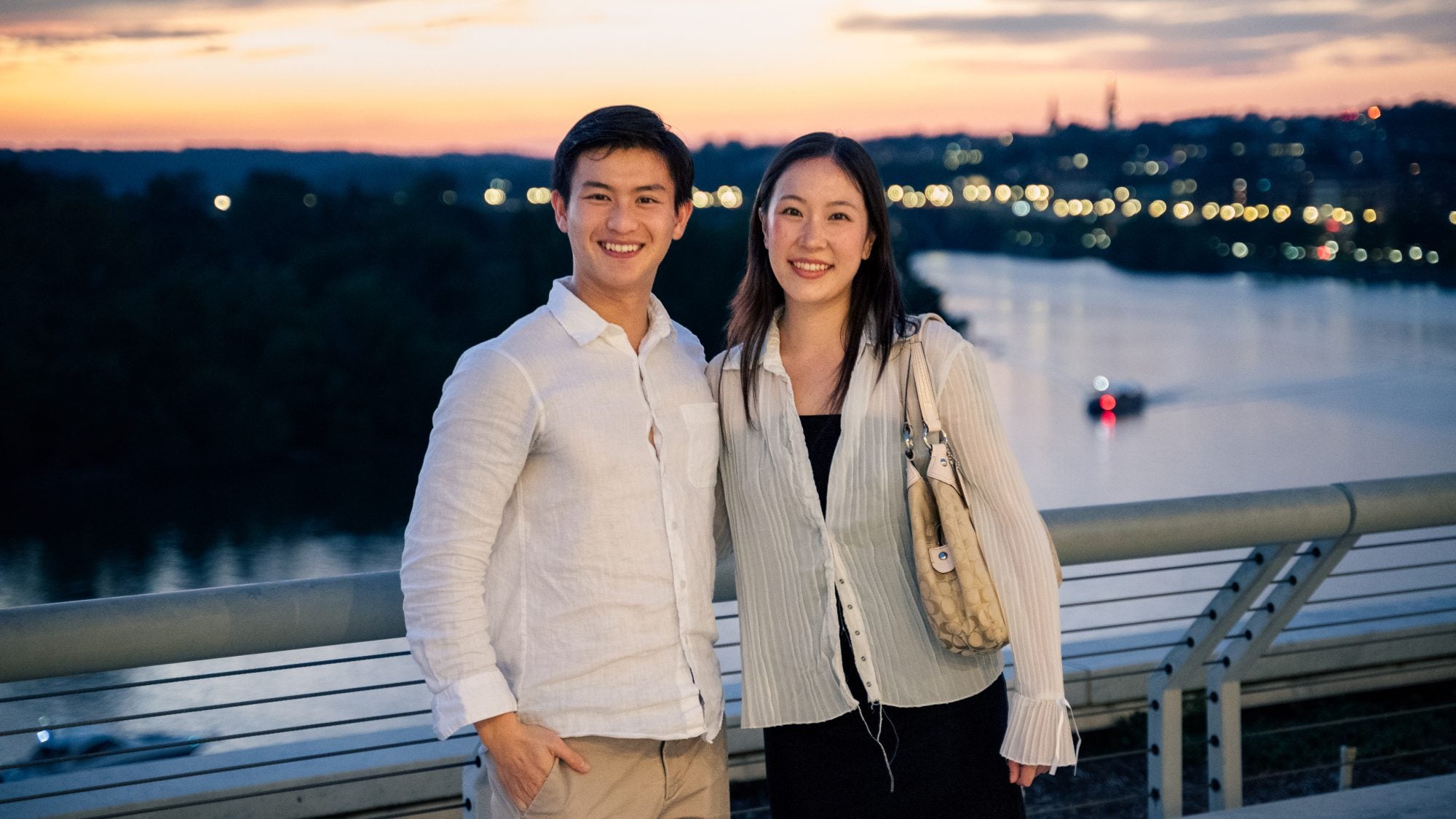 Young Asian man and woman overlooking Potomac river at sunset