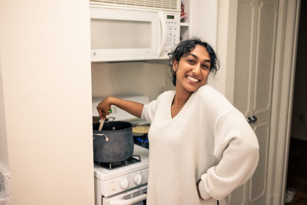 Young woman smiling while cooking in a large pot